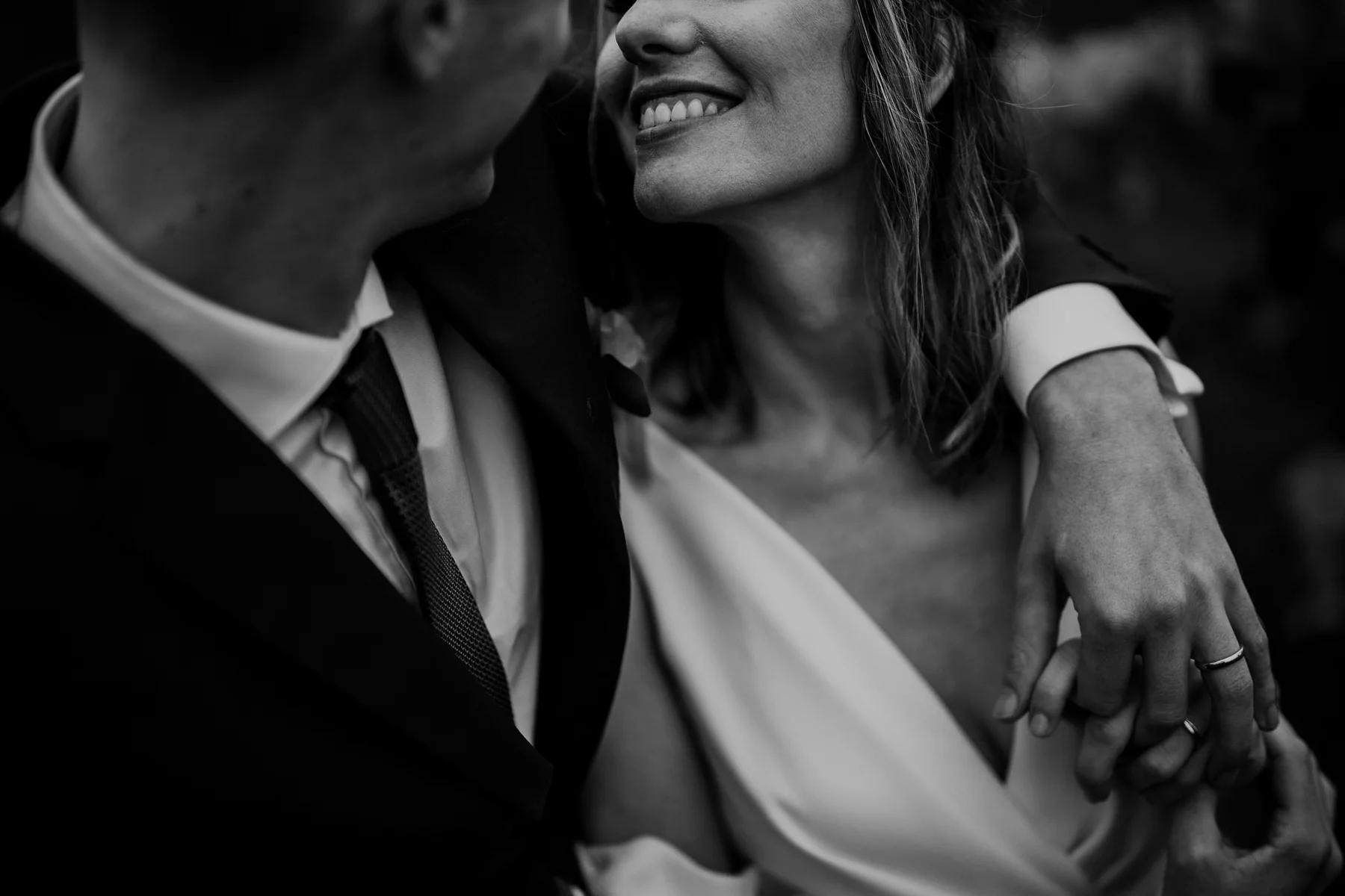 Dettaglio in bianco e nero degli sposi vicini, con la sposa sorridente